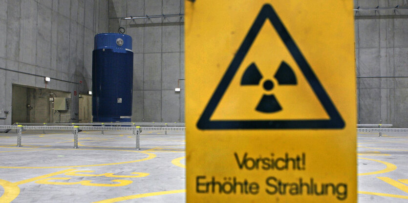 eine Halle, in der eine blauer Stahlbehälter zu sehen ist, im Vordergrund ein Schild mit der Aufschrift: "Vorsicht, erhöhte Strahlung!"