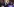 Donald Trump schüttelt Robert Kennedy hinter einem Stehpult die Hand. Im Hintergrund Publikum und viele Lichtpunkte