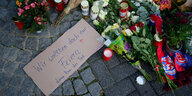 Trauergestecke liegen am Boden. Daneben ein Schild mit der Aufschrift: "Wir wollten doch nur feiern. Dann kam der Tod."