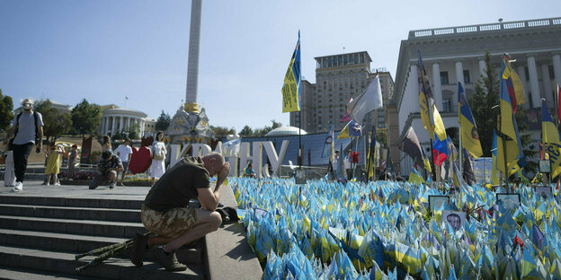 Ein Veteran erweist seine Ehrerbietung an einer behelfsmäßigen Gedenkstätte für gefallene ukrainische Soldaten im russisch-ukrainischen Krieg während des ukrainischen Unabhängigkeitstages auf dem Unabhängigkeitsplatz Majdan.