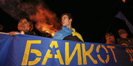 Menschen halten ein blaues Banner, auf dem „Boykott“ auf russisch steht