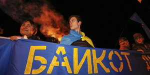 Menschen halten ein blaues Banner, auf dem „Boykott“ auf russisch steht