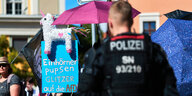 CSD in Bautzen, eine Demonstrantin hält ein Plakat: Einhörner pupsen Gltzer auf die AfD - auf dem Plakat sitzt ein dekoriertes Spielzeug-Einhorn, davor steht ein Polizist