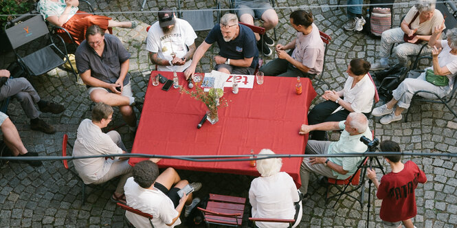 Viele Personen sitzen im Gespräch um einen Tisch