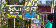 Demo-Plakate mit Slogans wie "Schule ist kein Boxring" und "Kinder frei von Gewalt" stehen vor einem Baum.