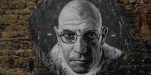 Ein schwarz-weißes Porträt von Foucault ist auf eine Mauer gesprüht