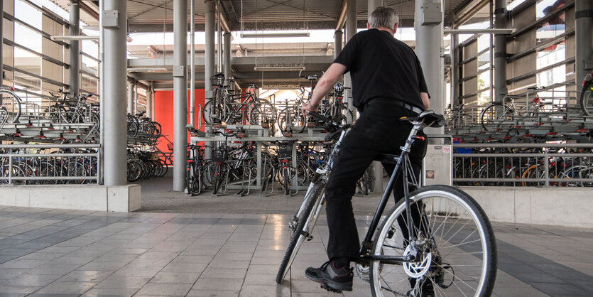 Ein Mann verlässt mit seinem Fahrrad das Fahrradparkhaus am Bahnhof