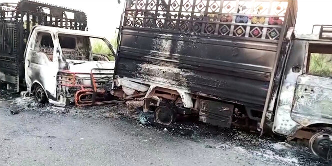 Verkohlte Fahrzeuge nach einem Angriff stehen am Straßenrand