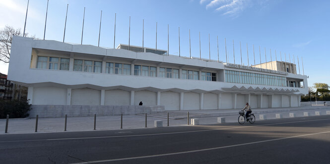 Eine Person fährt mit dem Fahrrad an dem Palazzo del Cinema auf dem Lido in Venedig vorbei.