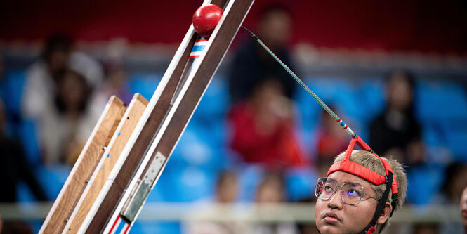 Para-Boccia Spieler stupst den Ball die Rampe runter