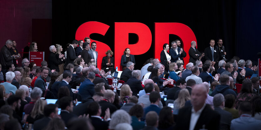 Delegierte stehen vor einem großen SPD Logo