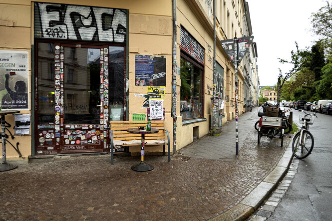 Geschlossener Späti auf einer Ecke, davor eine Bank, im Hinterrund auf dem Gehsteig geparkte Räder