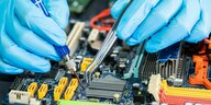 Nahaufnahme von Händen die ein circuit mainboard repariert