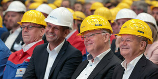 Olaf Scholz und Stephan Weil sitzen mit gelben Helmen auf dem Kopf bei einer Mitarbeitendenversammlung