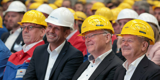 Olaf Scholz und Stephan Weil sitzen mit gelben Helmen auf dem Kopf bei einer Mitarbeitendenversammlung