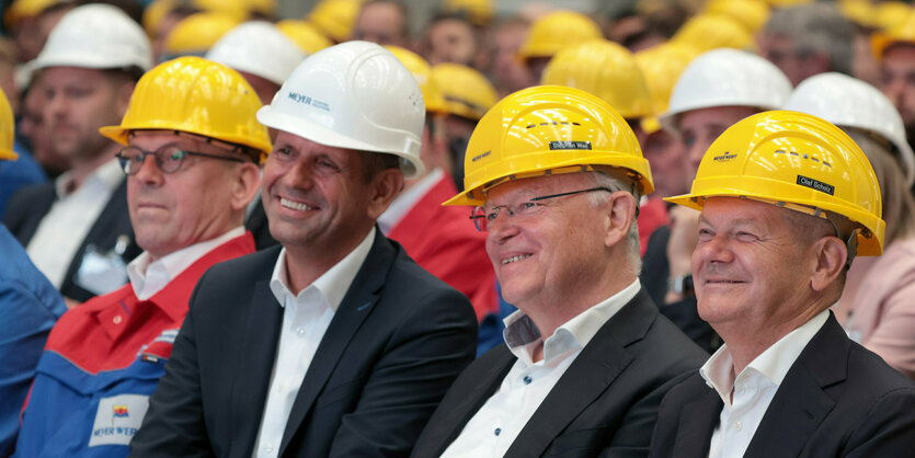 Olaf Scholz und Stephan Weil sitzen mit gelben Helmen auf dem Kopf bei einer Mitarbeitendenversammlung