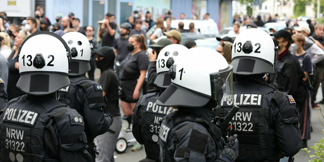 Polizisten stehen vor Demonstranten, die überweigend schwarze Kleidung und teilweise schwarze Masken tragen tr