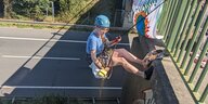 Eine Aktivistin in Kletterausrüstung lässt sich am Mittwoch in Achim über der leeren A 27 von einer Autobahnbrücke ab; an der Brücke hängt ein Plakat, zu sehen ist ein brennender Erdball