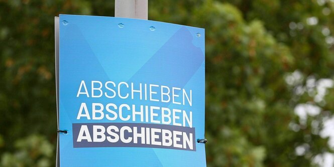 Auf einem Plakat mit blauem Hintergrund steht drei mal : Abschieben, Abschieben, Abschieben