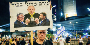 Ein Demonstrant hält ein Plakat, auf dem Bezalel Smotrich und Itamar Ben Gvir zu sehen sind, wie sie Ministerpräsident Netanjahu mit einem gelben Band erwürgen