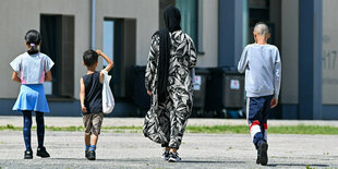 Eine Migrantin und ihre drei Kinder gehen über das Gelände der Zentralen Erstaufnahmeeinrichtung für Asylbewerber in Eisenhüttenstadt