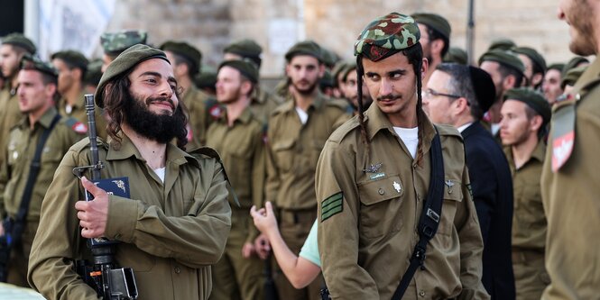 Zwei Soldaten mit Schläfenlocken tragen die Uniform der israelischen Armee und stehen in einer Gruppe von weiteren Soldaten