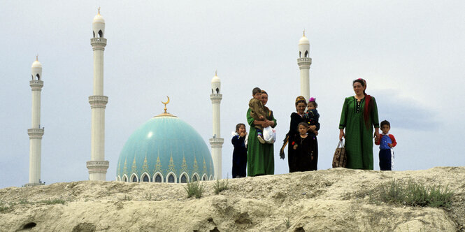 Frauen und Kinder in Turkmenistan stehen auf einem Hügel vor der Saparmurat Hadschi Moschee