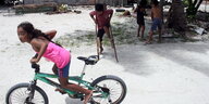 Kinder spielen, im Vordergrund fährt eines Fahrrad