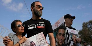 Menschen mit Plakaten, einer trägt ein T-Shirt auf dem "bring them home" steht