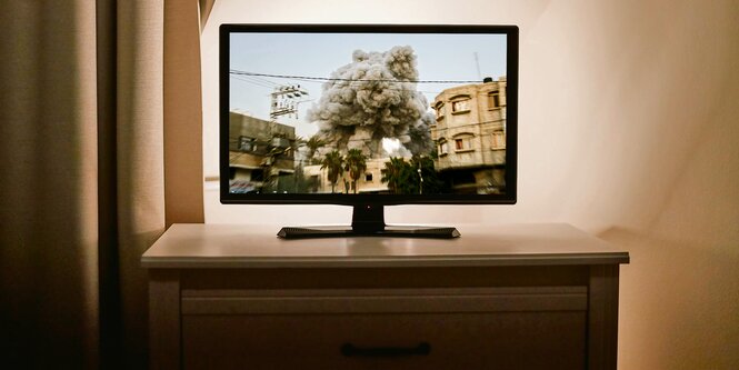 Montage eines Fernsehers, in dem eine Explosion in Gaza gezeigt wird.