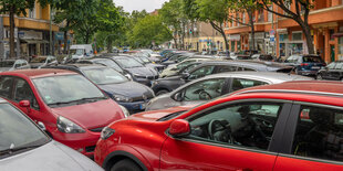 Auf einer Mittelinsel parken zahlreiche Autos in einer Straße