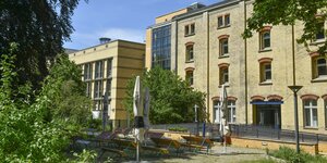 Das Bild zeigt das Kulturzentrum, ein gelbes Backsteinhaus, in der Lucy-Lameck-Straße in Neukölln