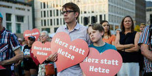 Ein Mann und ein Junge halten rote Herzen auf einer Demo