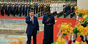 Senegals Präsident Bassirou Diomaye Faye begrüßt am Mittwoch mit Chinas Präsident Xi Jinping vor der Großen Halle des Volkes in Peking winkende Schulkinder.