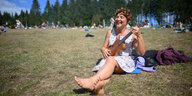 Eine Frau sitzt auf einer Wiese und spielt Ukulele.