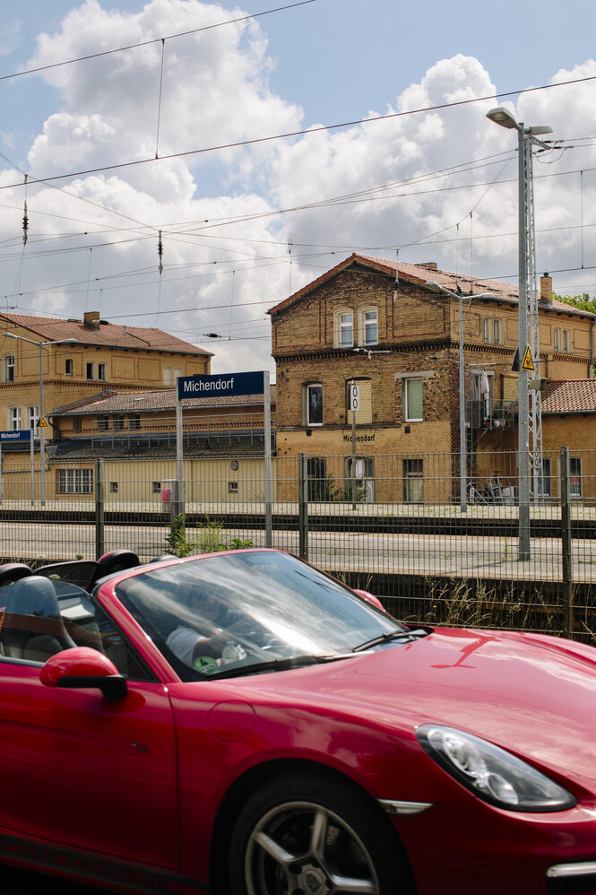 Ein roter Sportwagen steht vor dem Bahnhof von Michendorf