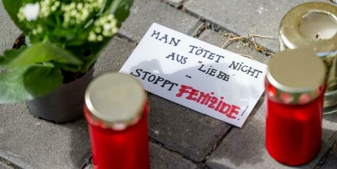 Blumen und Kerzen liegen nach einem tödlichen Messerangriff vor einem Hauseingang in Berlin-Friedrichsfelde neben einem Zettel mit der Aufschrift Man tötet nicht aus Liebe - Stoppt Femizide