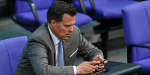 Gero Hocker sitzt im Bundestag undspielt mit seinem Smartphone