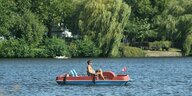 Ein Mann fährt mit einem Tretboot auf der Alster entlang.