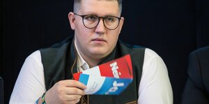 Maximilian Müger mit Brille. Er hält Stimmzettel in den Händen