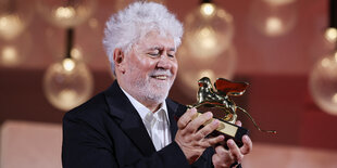 Pedro Almodóvar hält lächelnd seinen goldenen Löwen in der Hand