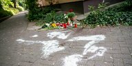 Kerzen und Blumen stehen und liegen in Berlin-Zehlendorf am Tatort