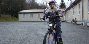 Junge auf Fahrrad vor Asylbewerberheim