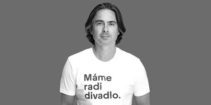 Porträt von Matej Drlička in einem weissen T-Shirt mit der Aufschrift: Mame radi divadlo (Wir mögen das Theater)