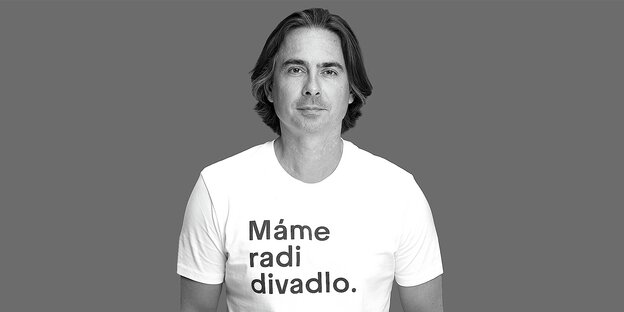 Porträt von Matej Drlička in einem weissen T-Shirt mit der Aufschrift: Mame radi divadlo (Wir mögen das Theater)