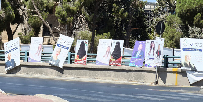 Auf Wahlplakatan sind eine Frau mit langen Haaren und eine mit verhülltem Gesicht zu sehen