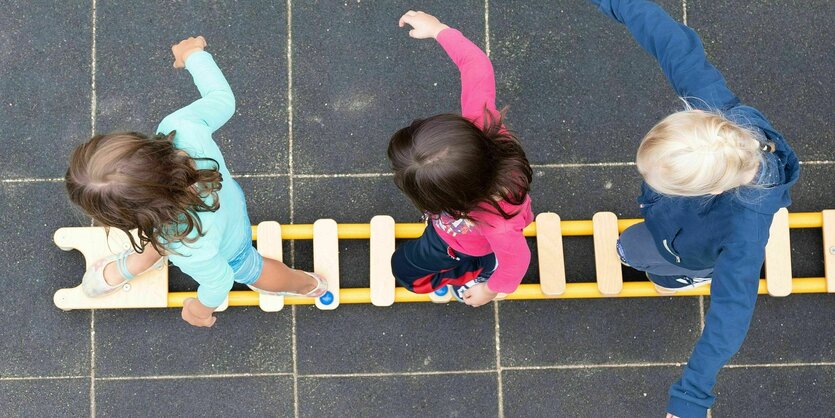 Kinder balancieren auf einer am Boden liegenden Leiter