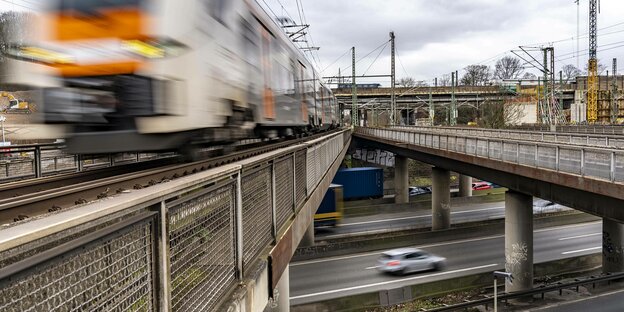 Ein Zug fährt über eine Autobahnbrücke