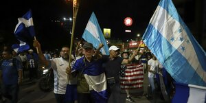 Menschen protestieren mit blau-weißen Fahnen