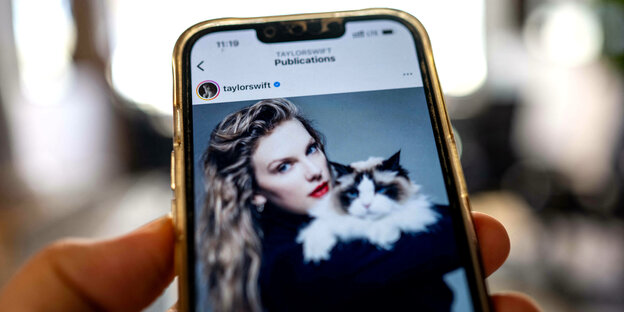 foto von Taylor Swift die mit einer Katze kuschelt auf einem Smartphone-Bildschirm den jemand in die Kamera hält